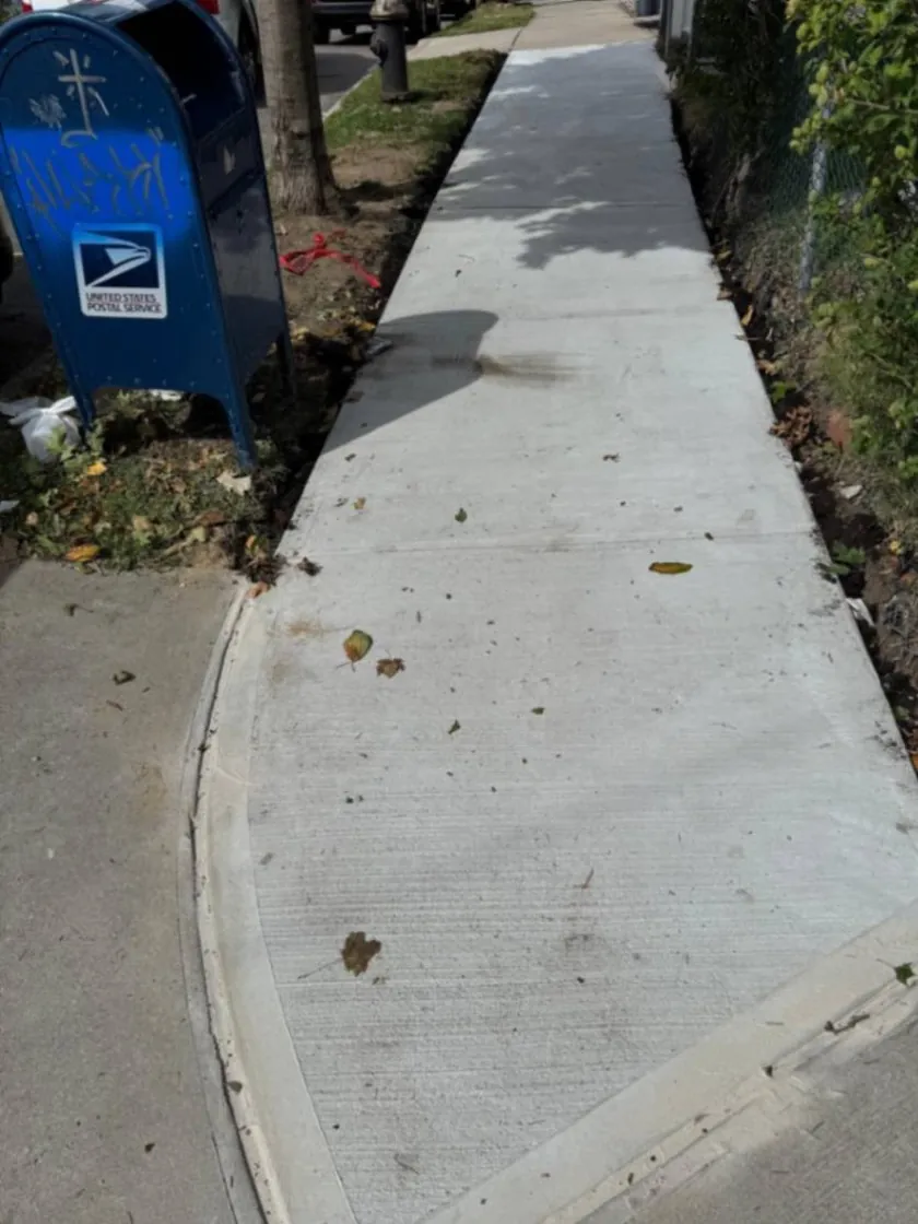New concrete sidewalk installation along a residential property in Jamaica, Queens